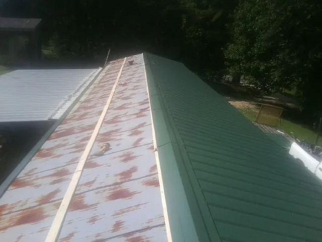 Old rusted panels beside newly installed green metal roofing — Wind Damage Roof Repair by Roofing Brothers in Weiser