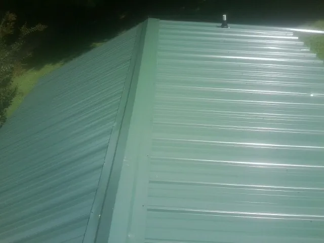 New green metal panels meeting at the ridge of a roof — Flat Roof Repair work by our crew in Weiser