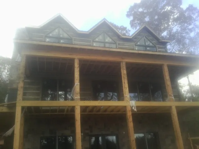 Dormers and porch framing on a large log home under construction — Roof Coating work by our crew in Weiser