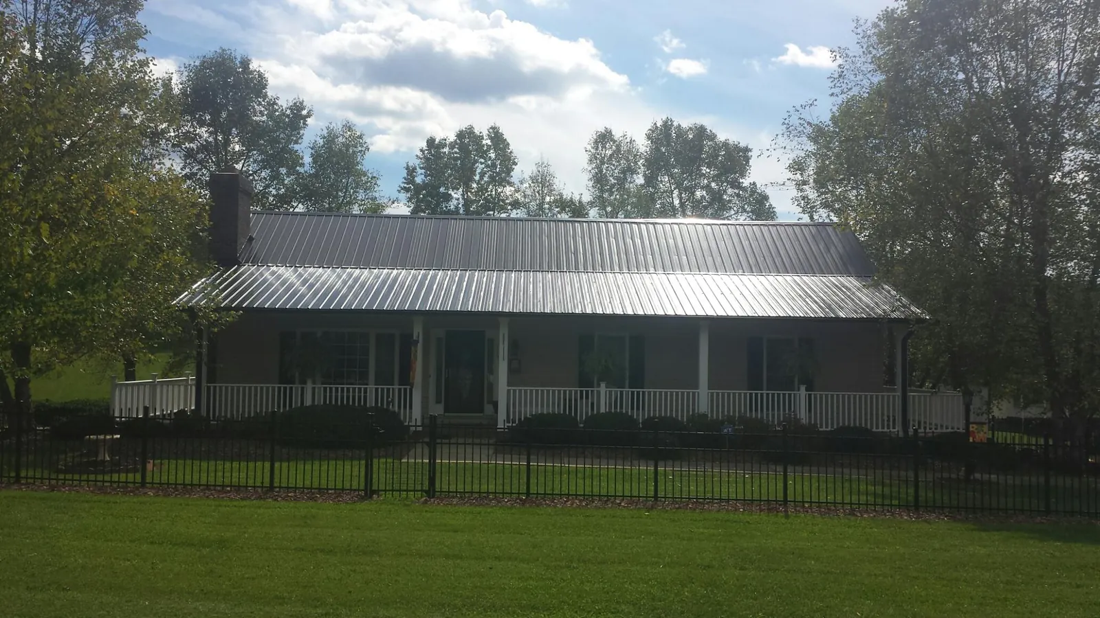 Gray metal roof on a brick ranch with a full width front porch — Gutter Guard Installation work by our crew in Weiser