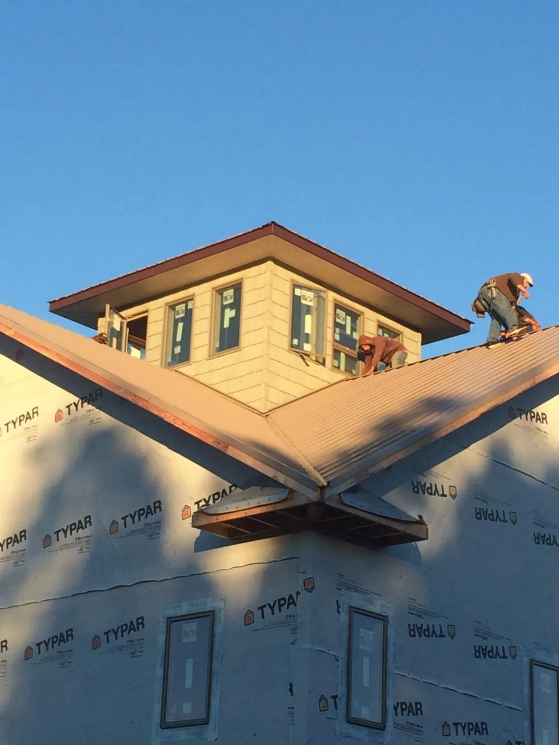 Roofers working around a rooftop cupola on a new metal roof at sunset — Roof Waterproofing in Weiser by Roofing Brothers